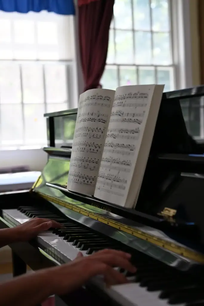 An adult student playing piano at Lifelong Music School in Hunterdon County, NJ. He is reading sheet music while playing a prelude from Bach's Well-Tempered Clavier.